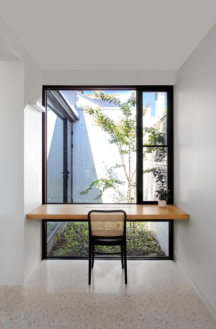 an empty room with a table and chair in front of a large window that looks out onto the backyard