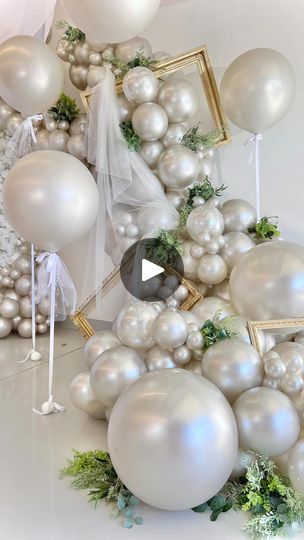 an arrangement of white balloons and greenery