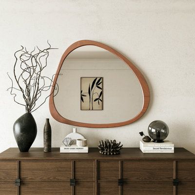 a wooden dresser topped with a mirror and vase