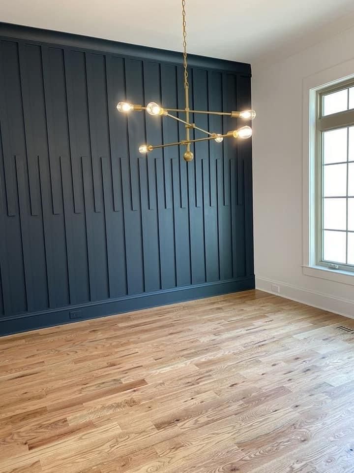 an empty room with wood flooring and blue painted paneled walls in the background