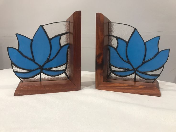 two blue stained glass vases sitting on top of a white cloth covered tablecloth