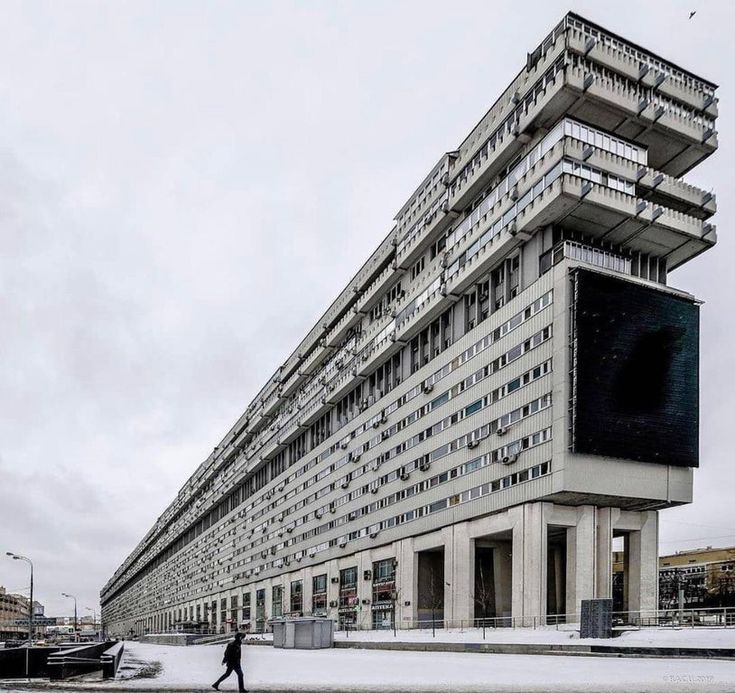 a person walking in front of a tall building on a snowy day with no one around