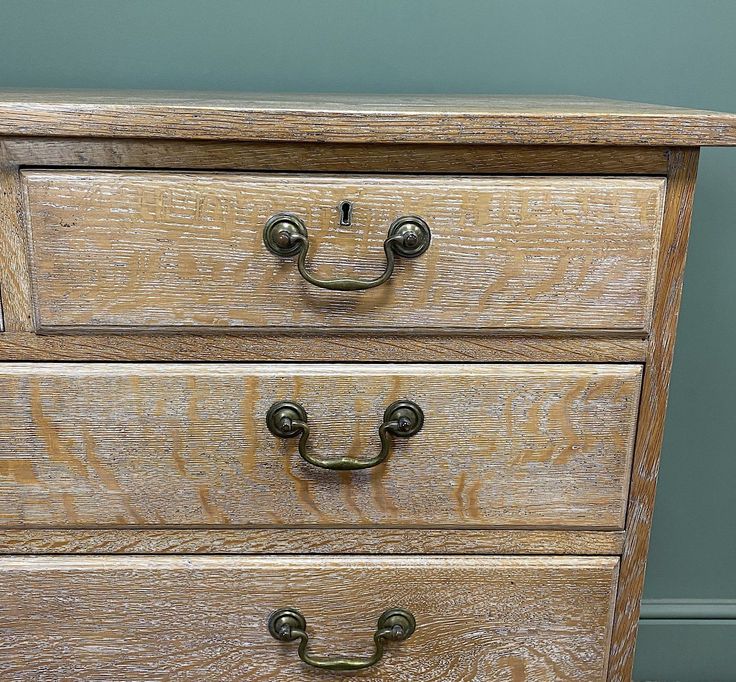 a wooden dresser with three drawers and two handles