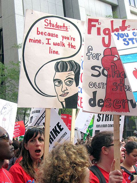 a group of people holding protest signs in front of a building with posters on them