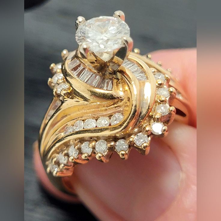 a close up of a person holding a gold ring with diamonds on the sides and an oval shaped diamond in the middle