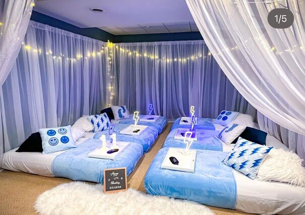 the beds are decorated with blue and white decor for a party or wedding reception at night time