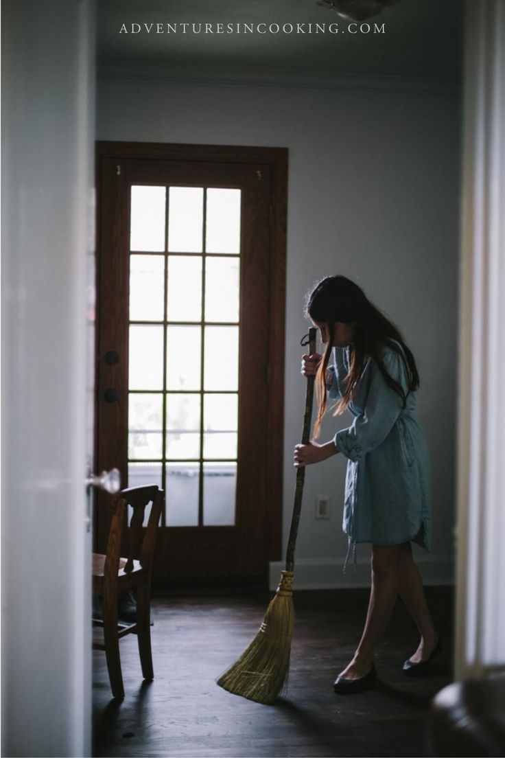 a woman sweeping the floor with a broom