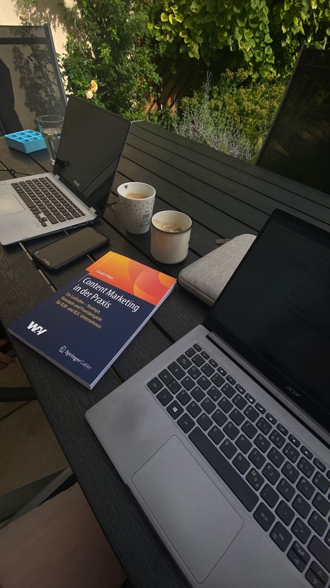 two laptops are sitting on a table outside