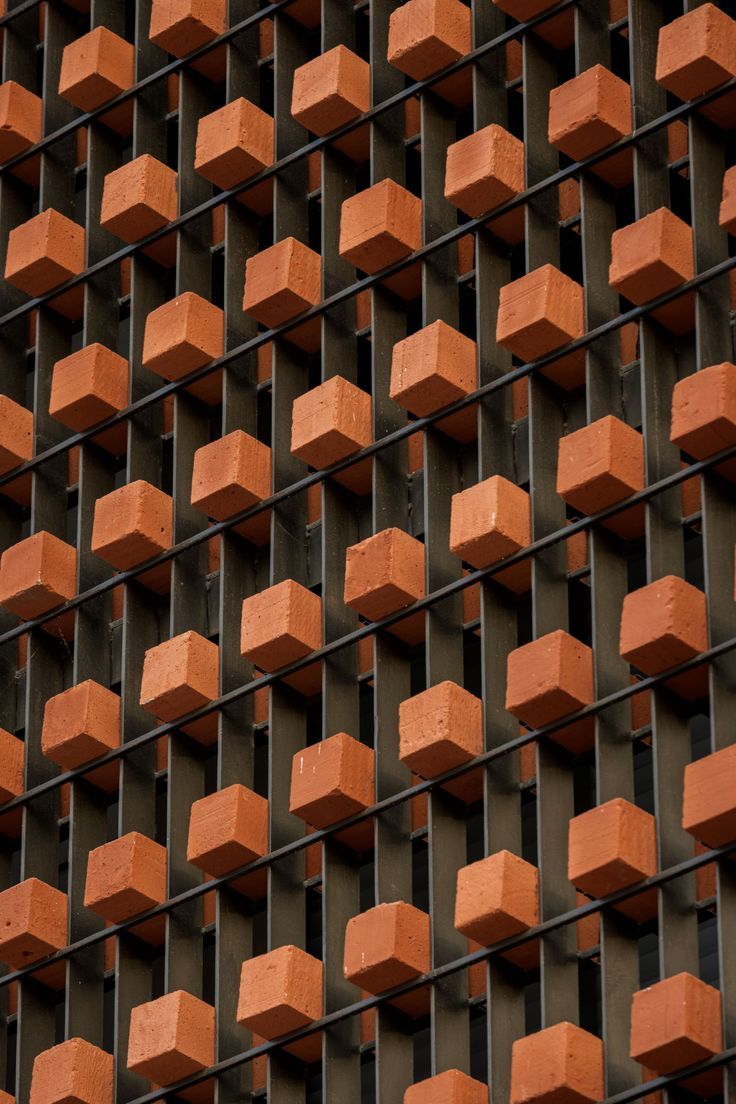 an orange brick wall that is made out of metal bars and has cubes on it