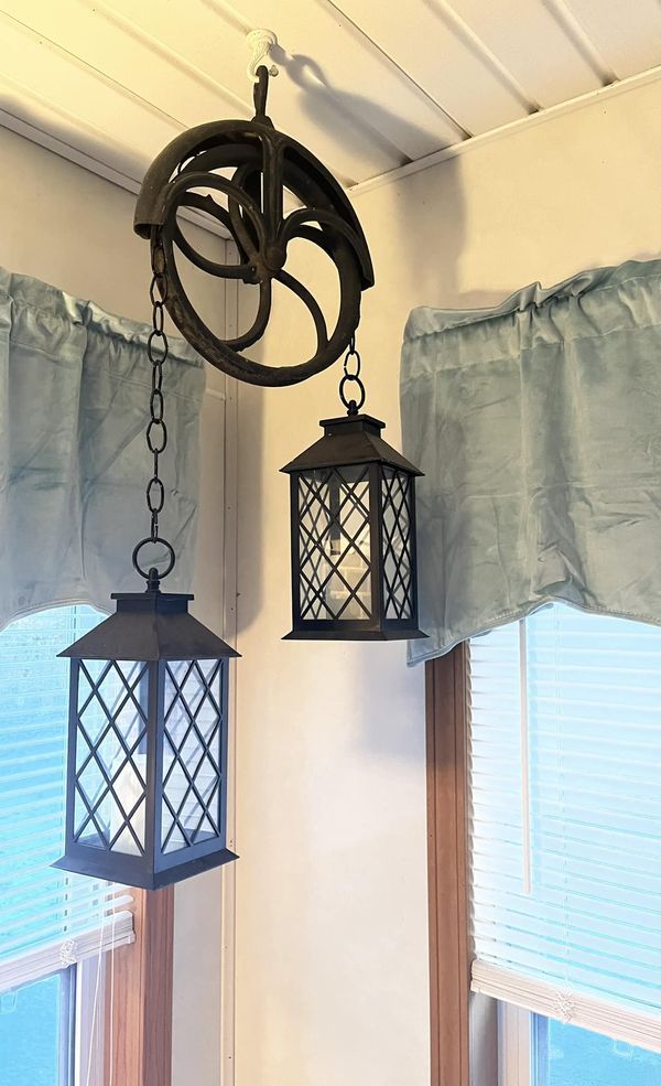 two lamps hanging from the ceiling in front of windows with blue drapes on them