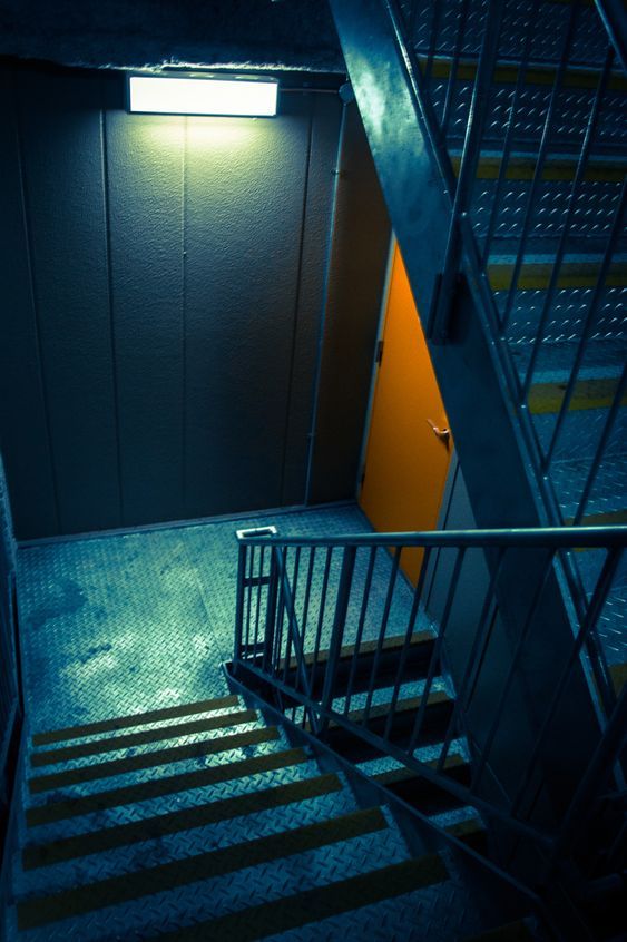 an empty stairwell with stairs leading up to the door and light coming in from above