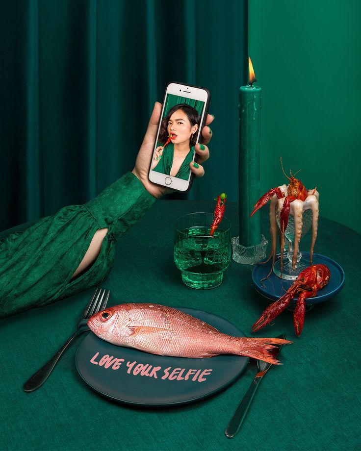 a woman taking a selfie with her cell phone while sitting at a dinner table