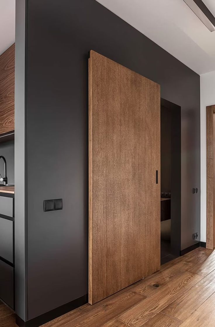 an open door in the middle of a room with wood floors and black painted walls