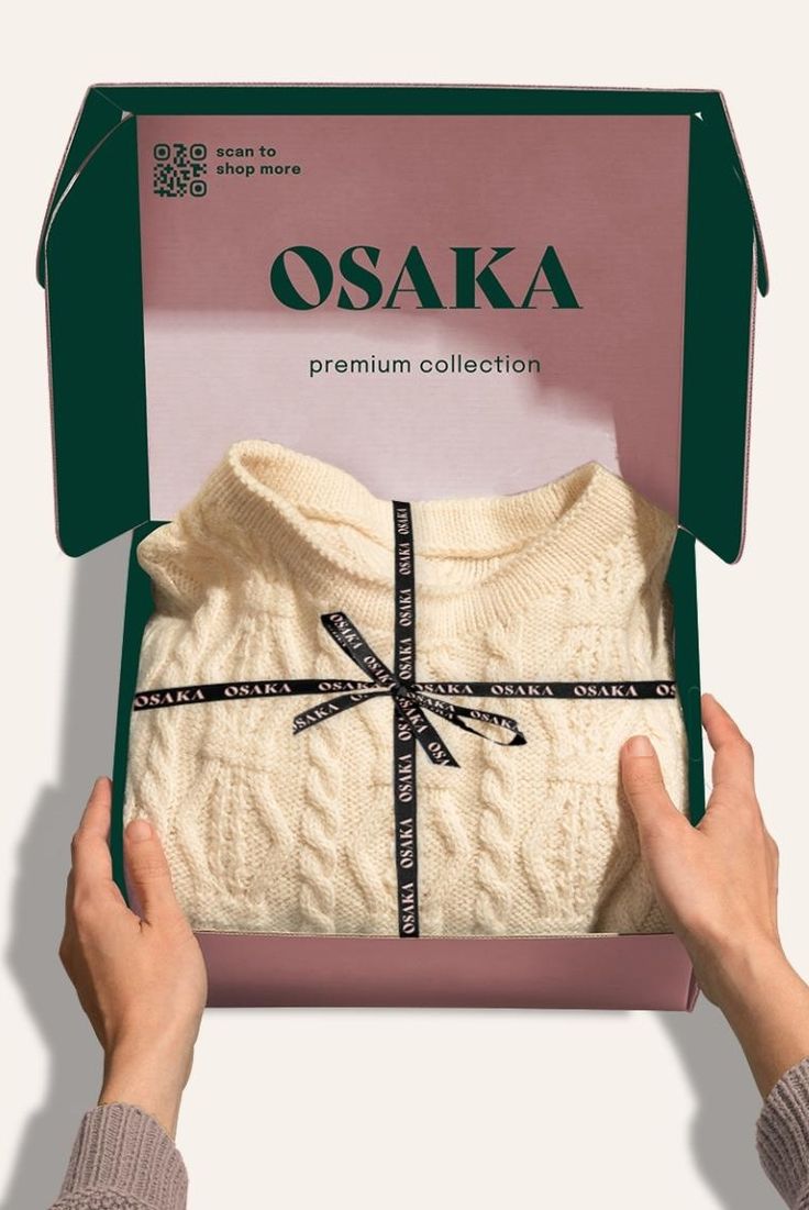 a person is holding up a box with a sweater in it's front and back