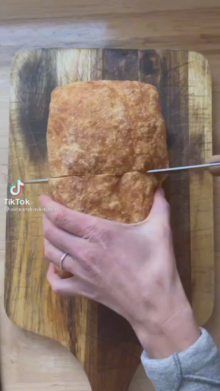 This may contain: a person is cutting bread on a wooden board