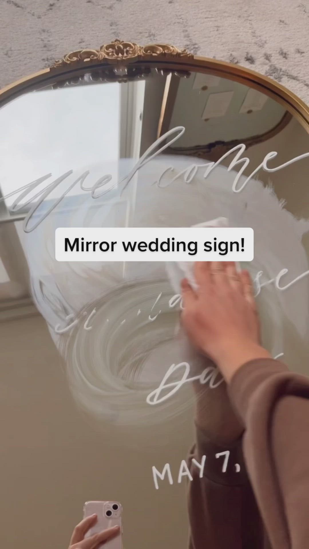 This may contain: a woman wiping off her wedding sign in front of a mirror with the words mirror wedding sign written on it