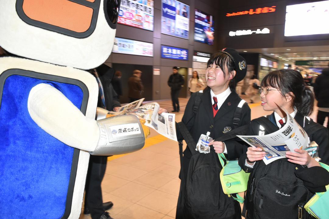 ロボスケから「号外」を受け取る駅利用者=水戸市宮町
