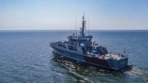 A patrol ship called the Raju sails on the sea on a sunny day