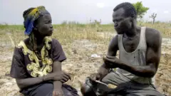 Nyakuma and her husband Sunday sitting in the grass