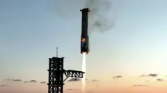 The booster from the Starship rocket is shown landing between two mechanical arms with flames emitting from its base