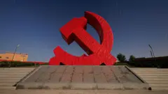 A sculpture of the Chinese Communist Party logo - a hammer and sickle in red.  