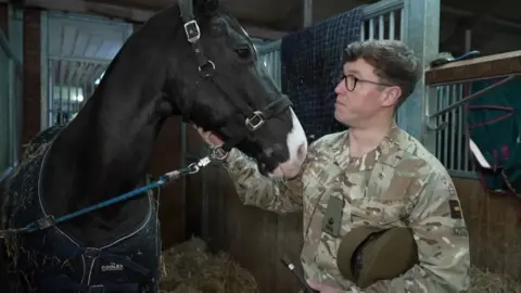 Major Samuel Littlejohn looks at Jake, one of the horses leading the gun team