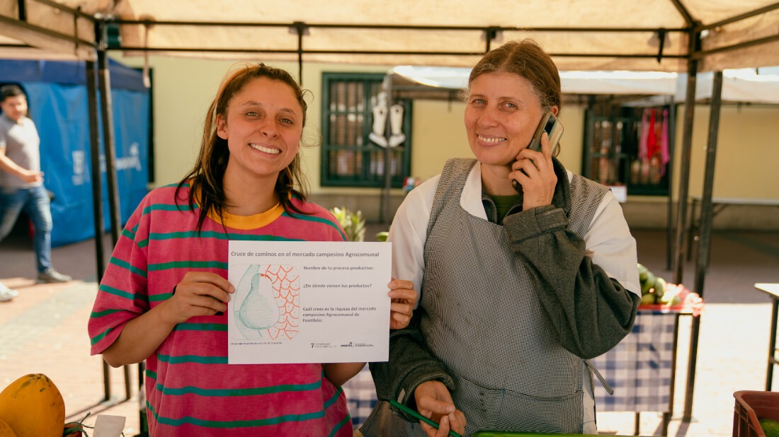 Mujeres sonriendo con su dibujo durante la actividad en el mercado agrocumunal de fontibón