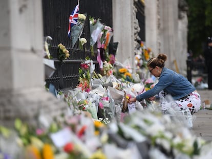 Una mujer deja flores en las verjas del Palacio de Buckingham un día después de la muerte de Isabel II, este viernes, en Londres.