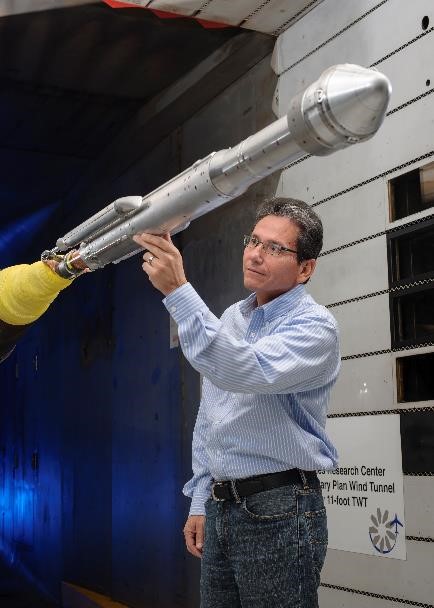 An engineer works with a model of a United Launch Alliance Atlas V rocket with a Boeing CST-100 Starliner capsule inside a wind tunnel.