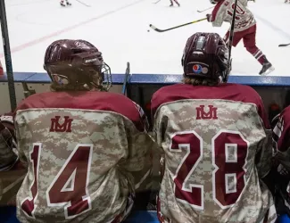 Hockey players watch a game from the bench