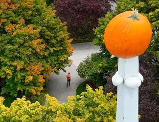 A pumpkin speared atop a Main Hall spire overlooks campus below