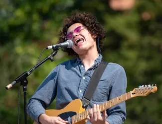 A student sings and plays guitar during an outdoor event held on UM&apos;s Oval