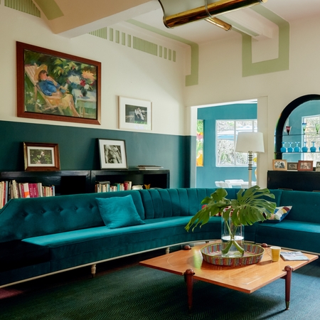Ett ljust och luftigt vardagsrum med en turkos soffa.