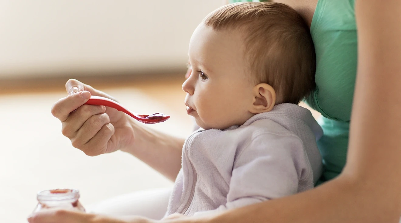 mother feeding baby food to baby at home