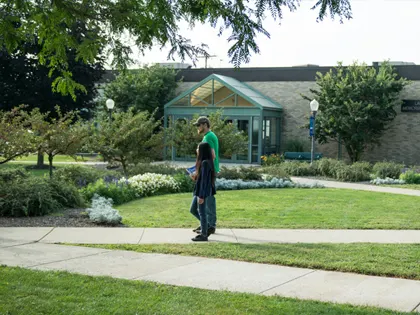 Two people walking on a sidewalk on campus at Penn State Shenango.