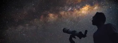 Man with telescope looking at stars and galaxy