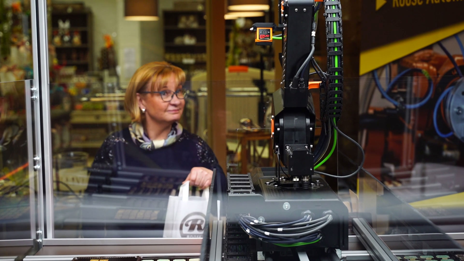 woman stands in behind a robot