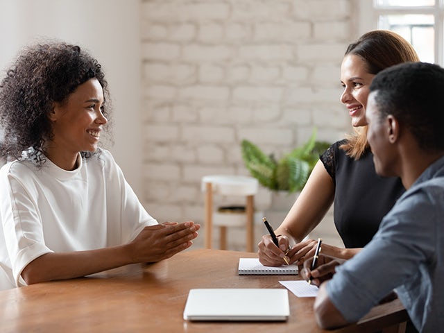 Conference room meeting between three people sitting at a table