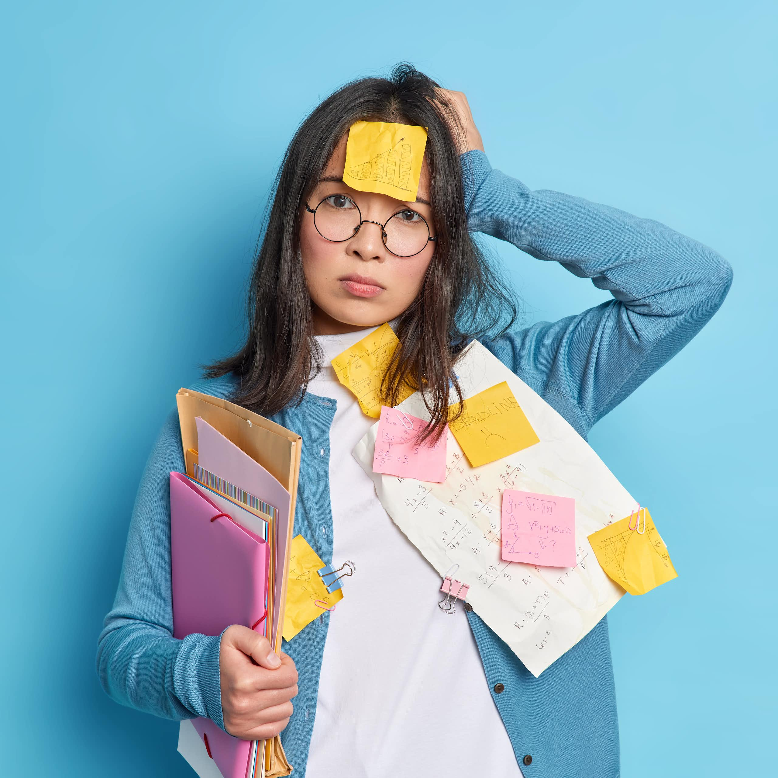 Forgetful woman covered in post-it notes and papers.