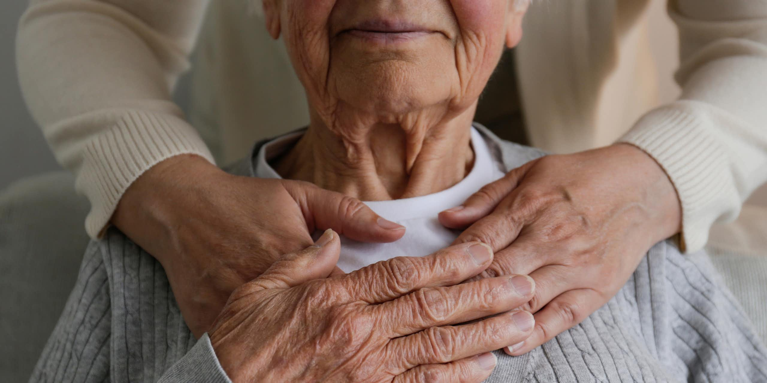 Femme méconnaissable qui s'occupe d'une vieille dame, la serrant dans ses bras derrière la main.