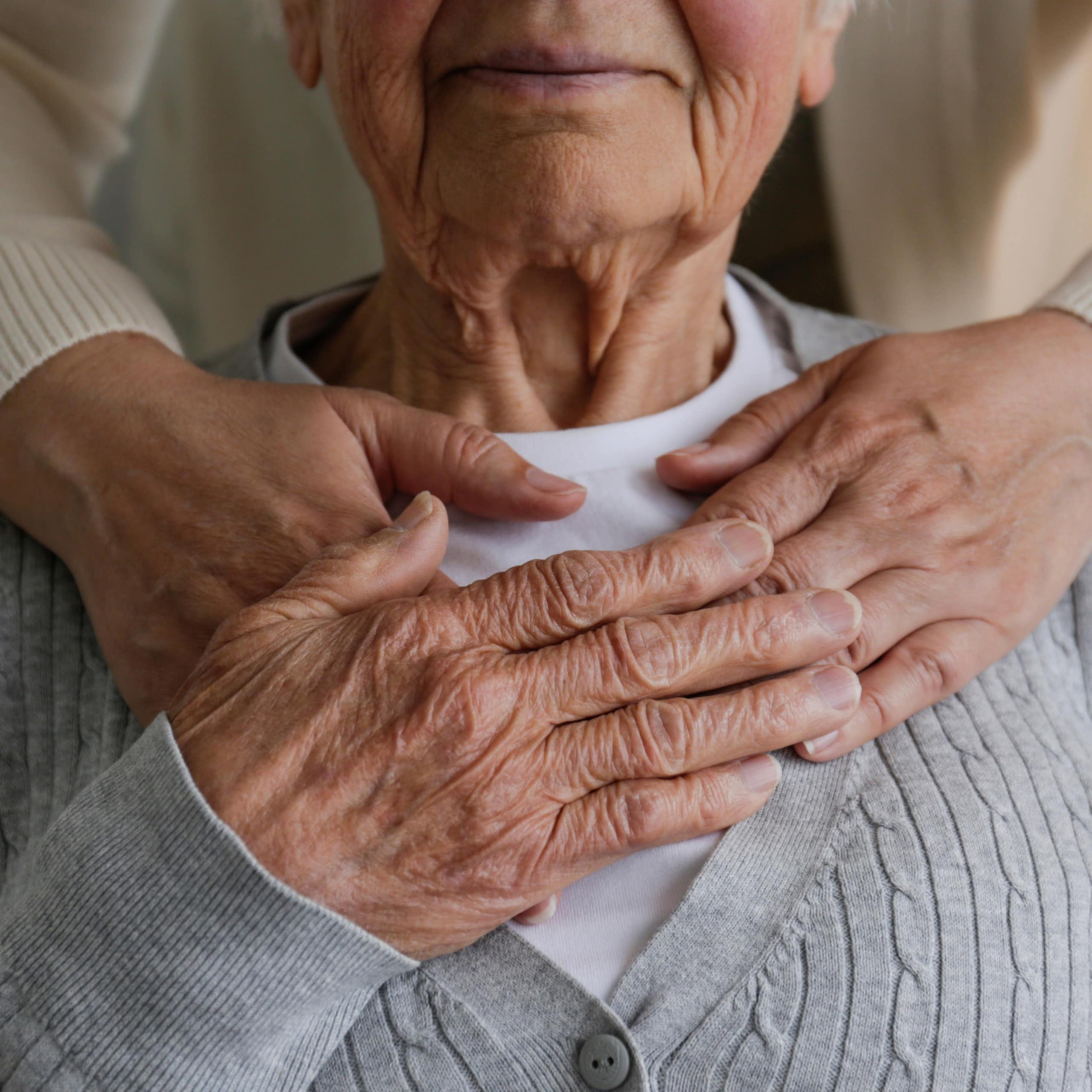 Femme méconnaissable qui s'occupe d'une vieille dame, la serrant dans ses bras derrière la main.