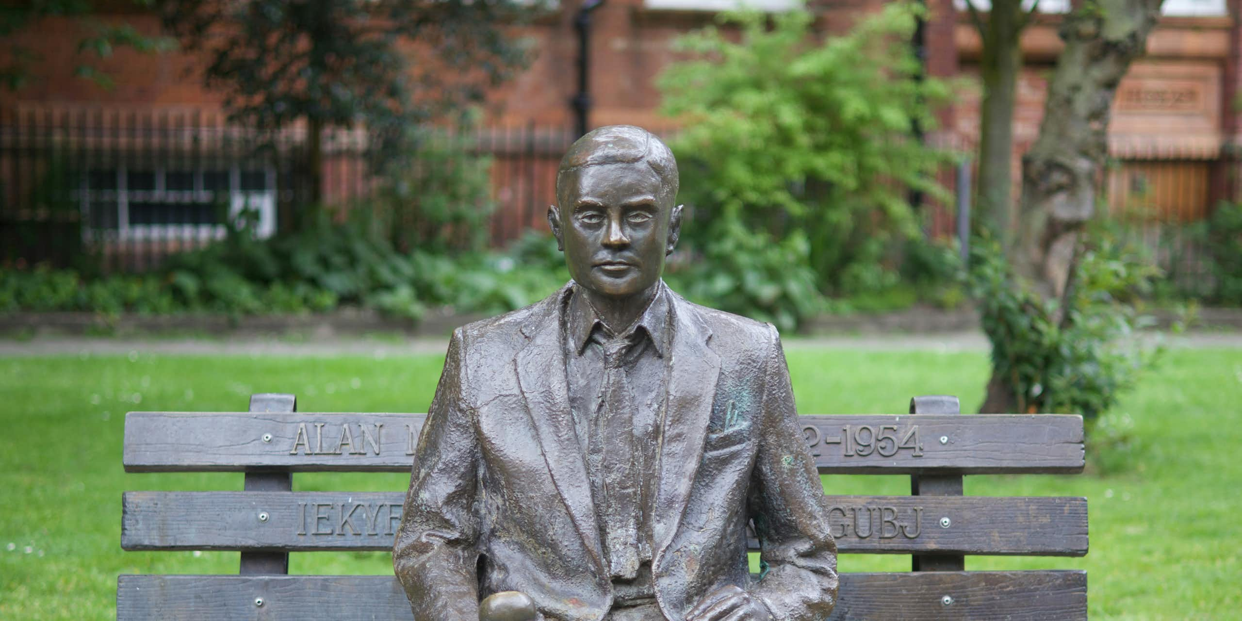 Statue d'Alan Turing assis sur un banc, une pomme dans la main, à Manchester.