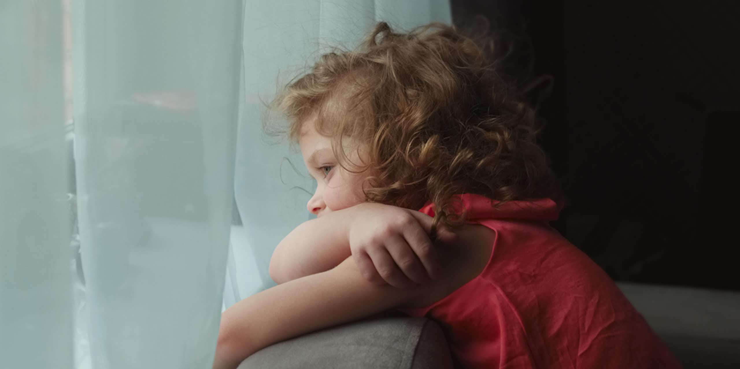 Petite fille qui s'ennuie devant une fenêtre