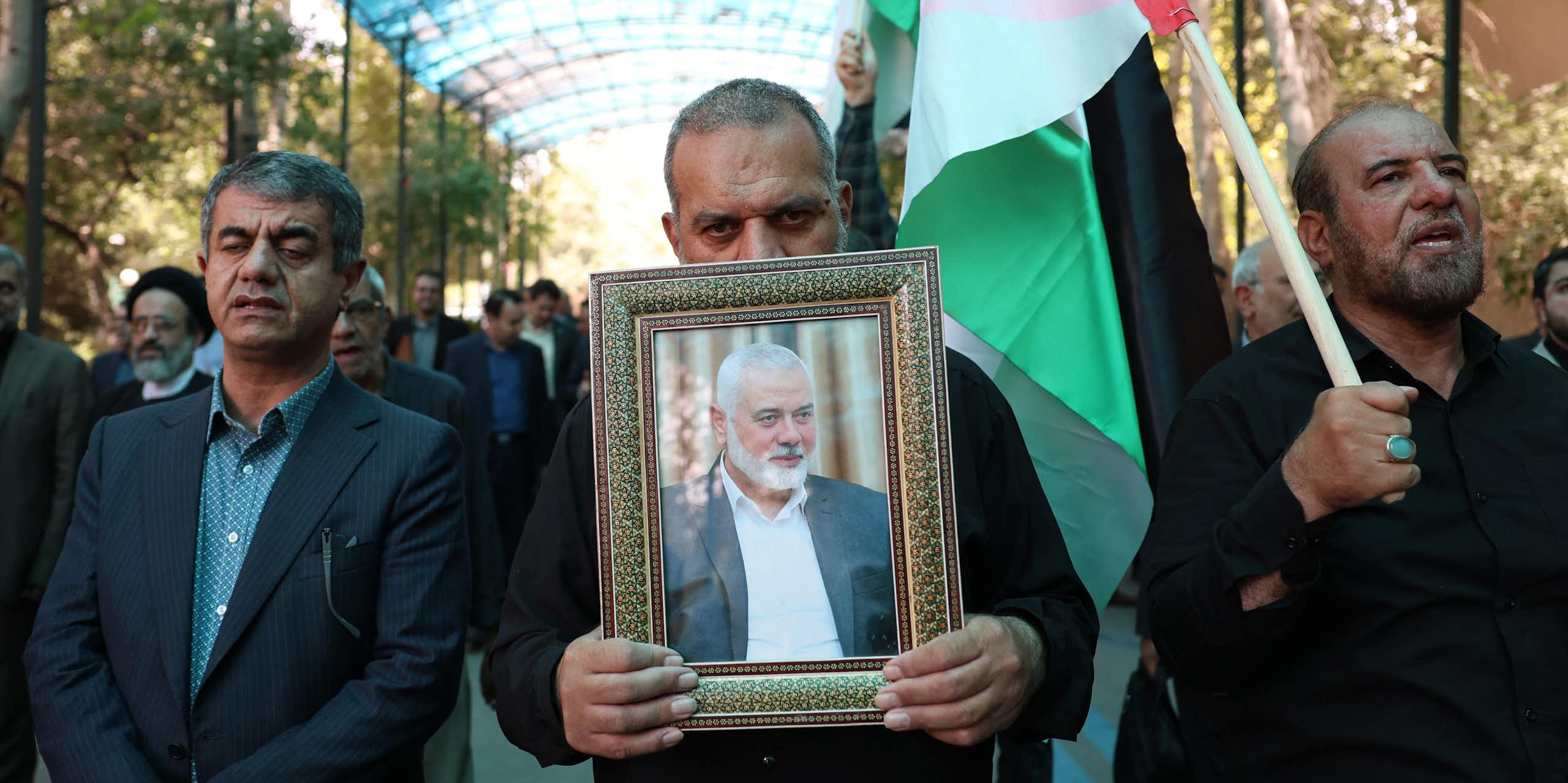 Des hommes portent le portrait d'Ismaïl Haniyeh et un drapeau palestinien