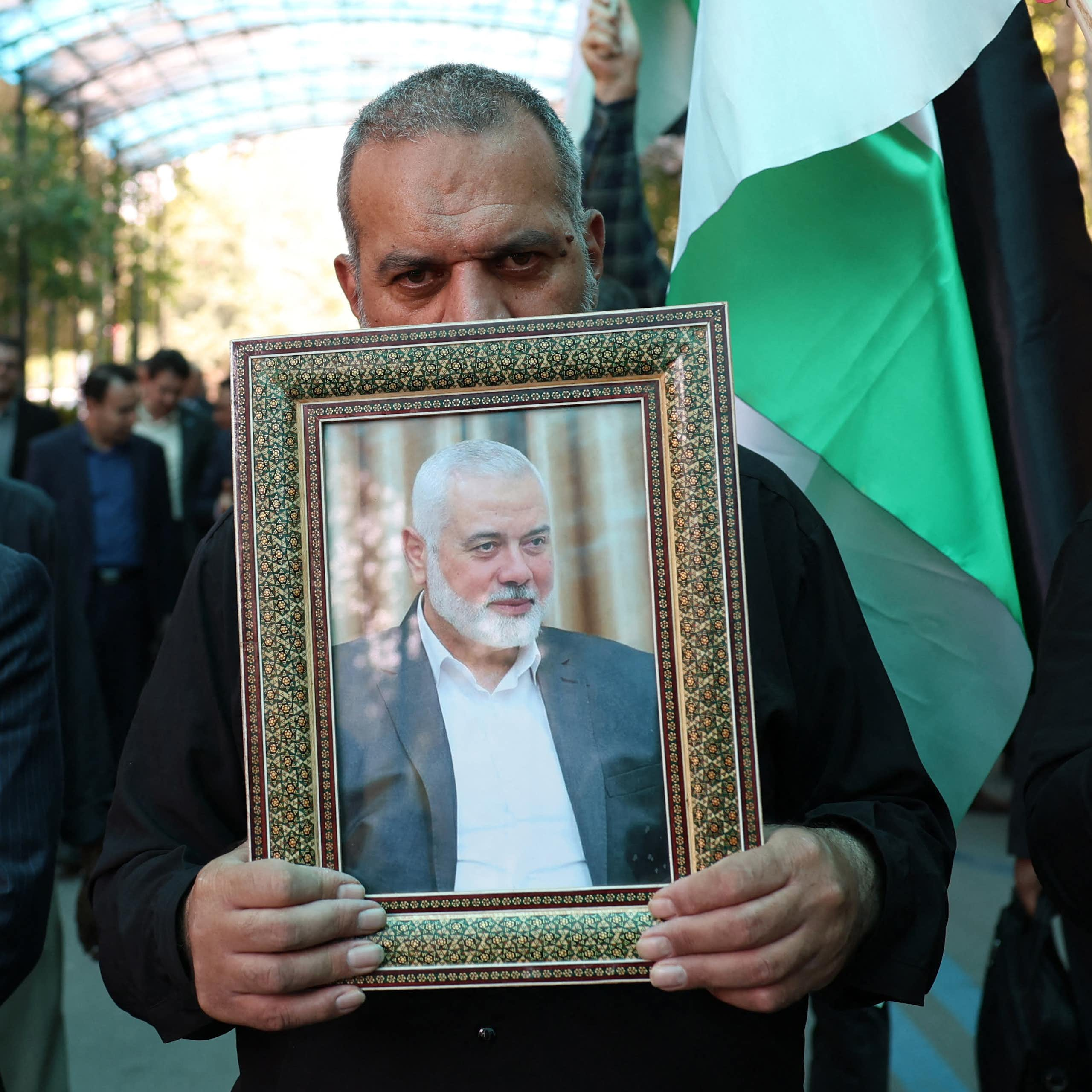 Des hommes portent le portrait d'Ismaïl Haniyeh et un drapeau palestinien