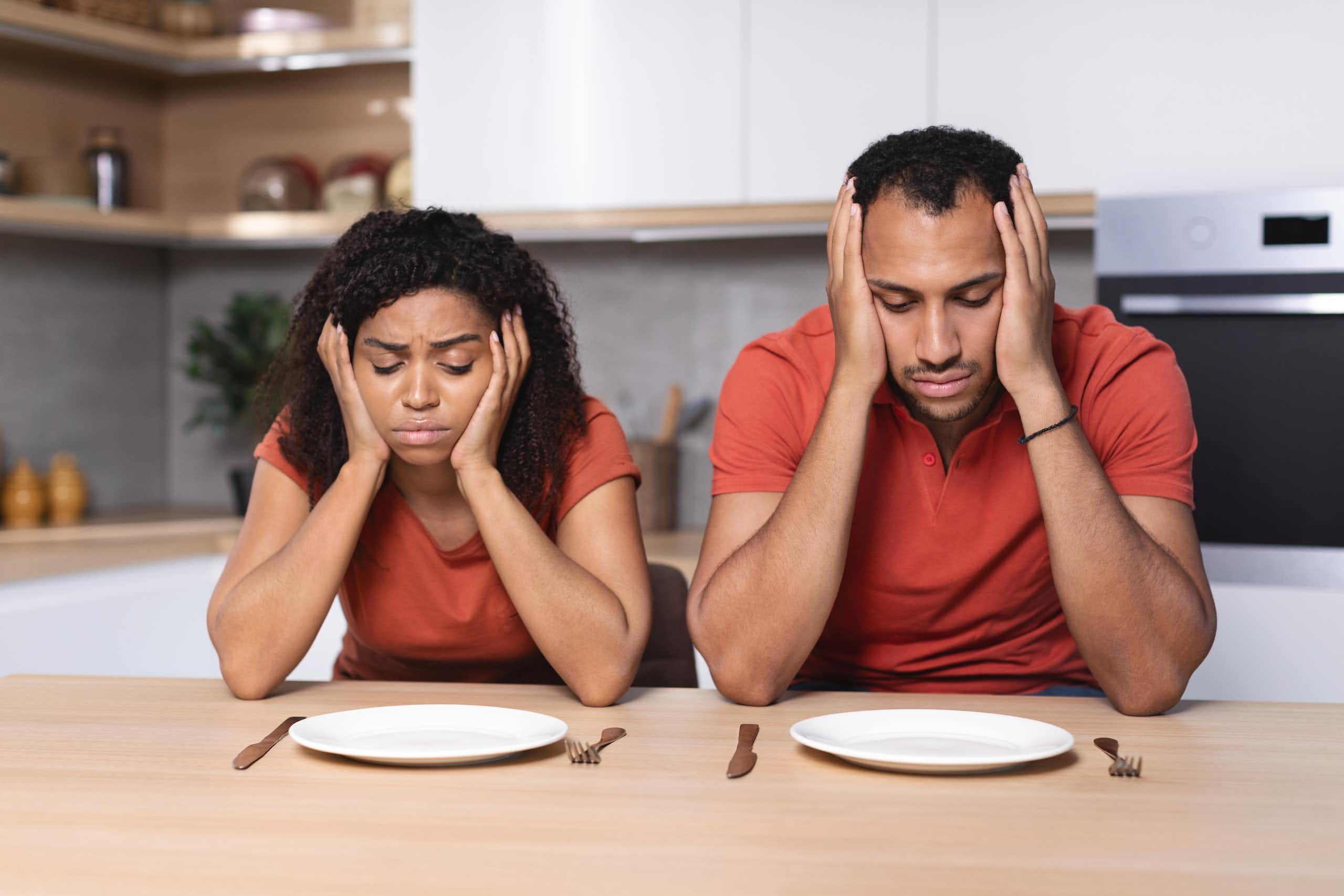 Un homme et un femme semblent affamés et boudent devant leurs assiettes vides.