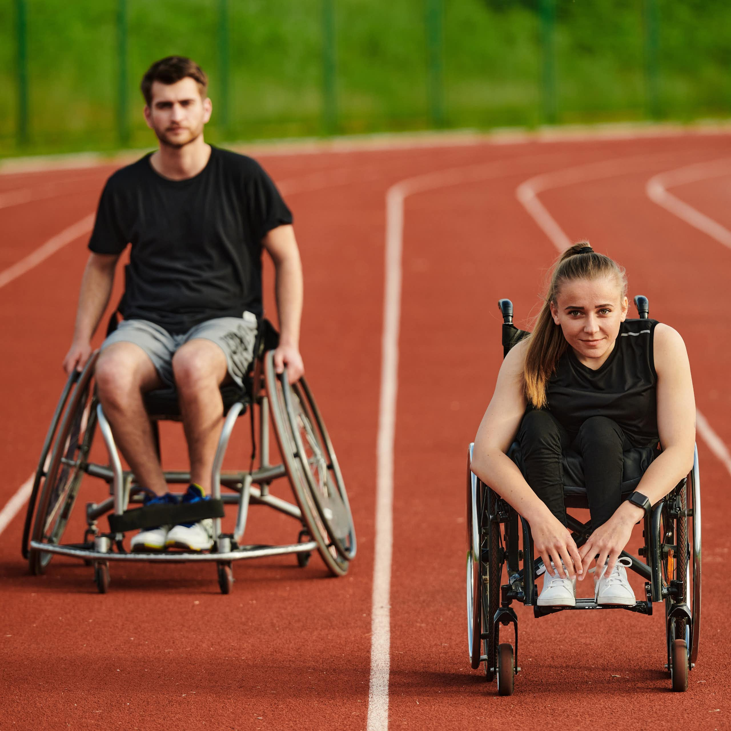 Un homme et une femme en fauteuil sur une piste d'athlétisme.