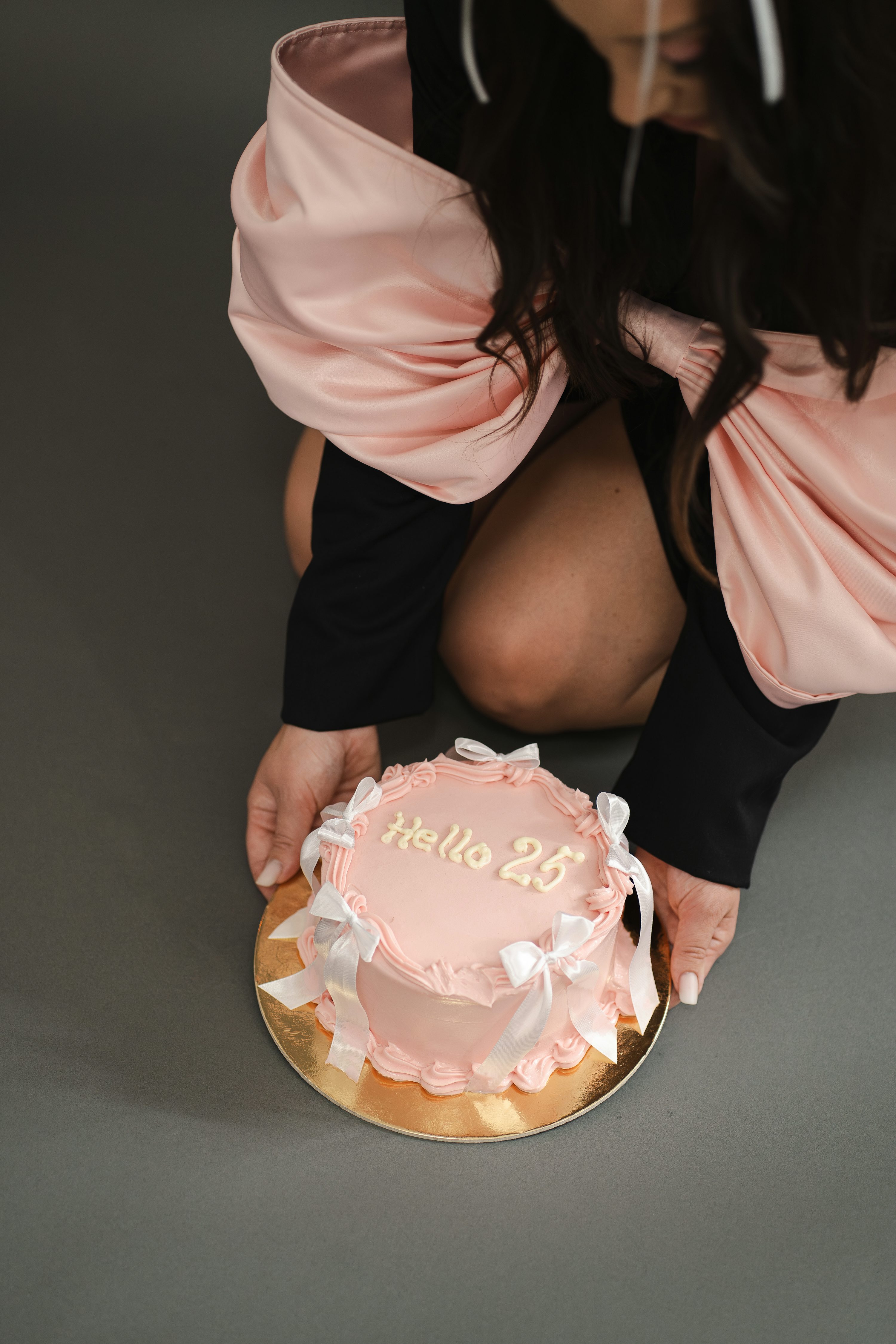 A woman kneeling down with a cake in front of her