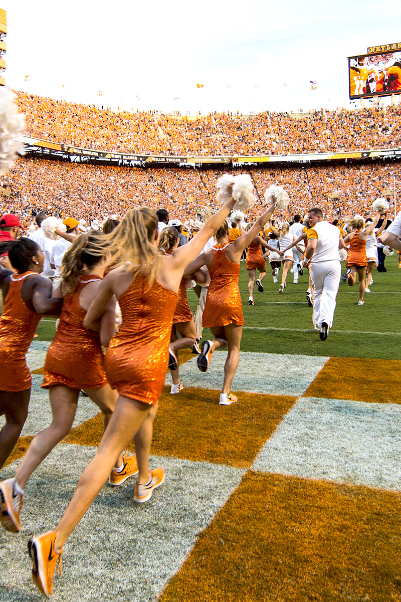 cheerleaders rush the field during a packed home game