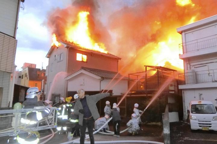 新町商店街で起きた火災で消火活動を続ける消防隊員ら＝２４日午前７時１０分ごろ、八幡浜市